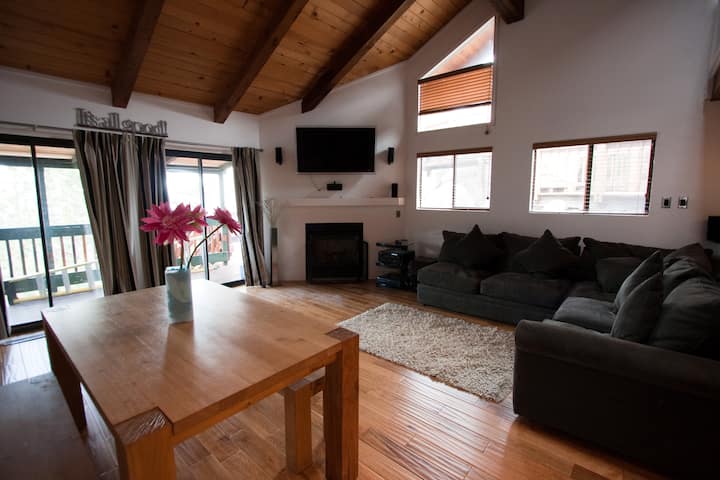 Living room with an L-shaped couch, flat screen television and the dining table beyond