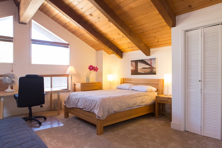 Loft bedroom with a queen bed beneath a sloping ceiling
