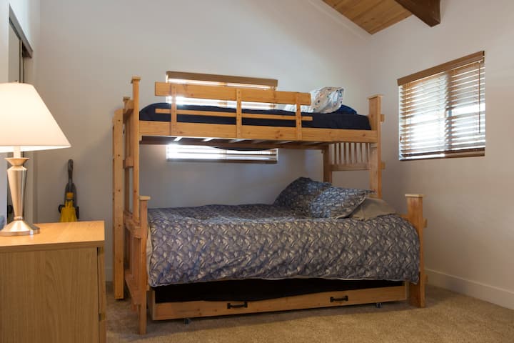 Upstairs bedroom with a made-up bed and window to the trees