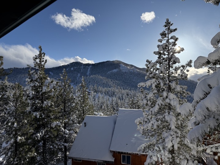 Snow-covered pines, rooftops and the ski mountain seen from the deck in winter